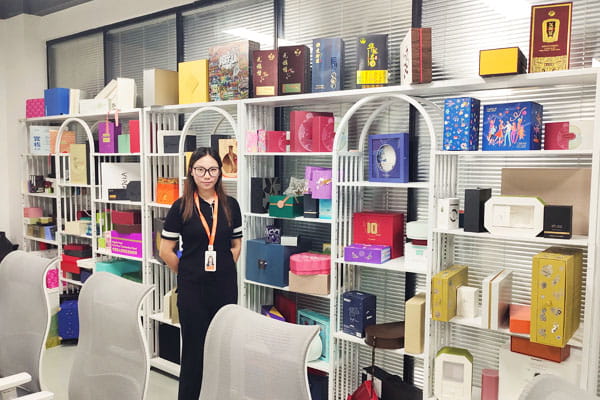 Manager at a Chinese packaging factory beside a collection of finished boxes